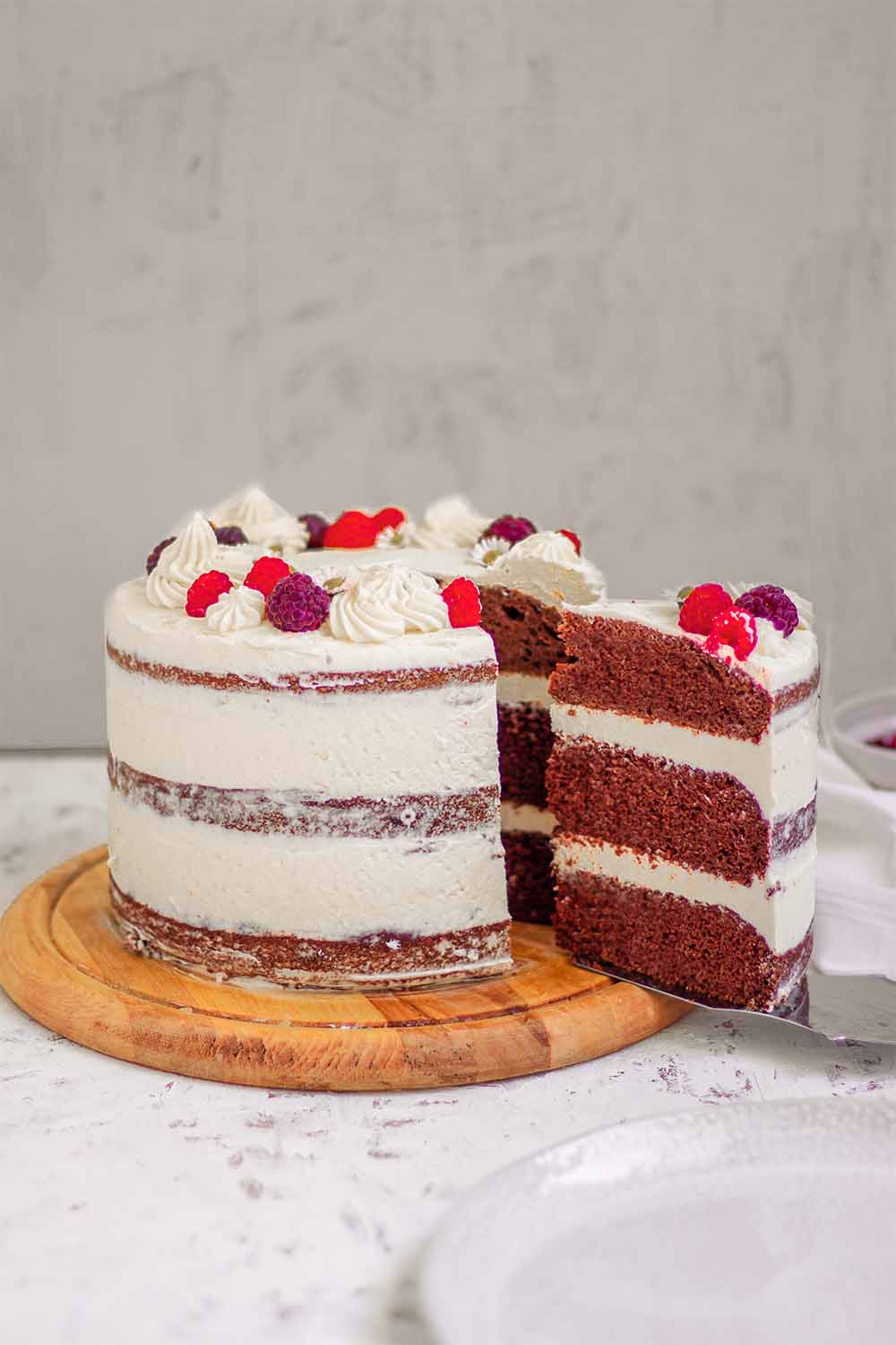 Slicing gluten-free and vegan chocolate cake with vanilla frosting